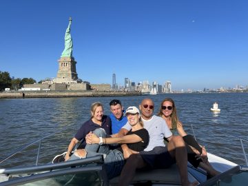 people on a boat with Lady Liberty in the background