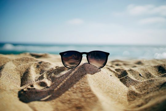 image of a beach and sunglasses in sand