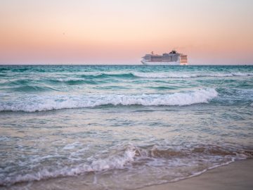 Cruise ship on the ocean. Luxury liner at sea. Miami Beach with cruise ship. Sea water and cruise liner. Tourist cruise ship near coast. Ocean waves and vessel boat. Summer dream vacation. Boat trip